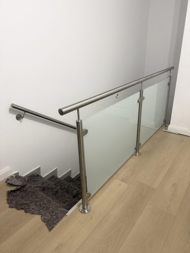 Handlauf und Geländer Handlauf für einen Treppenniedergang mit Geländer aus Edelstahl Oberfläche geschliffen K240.
Geländer Mit Milchglas als Füllung.
